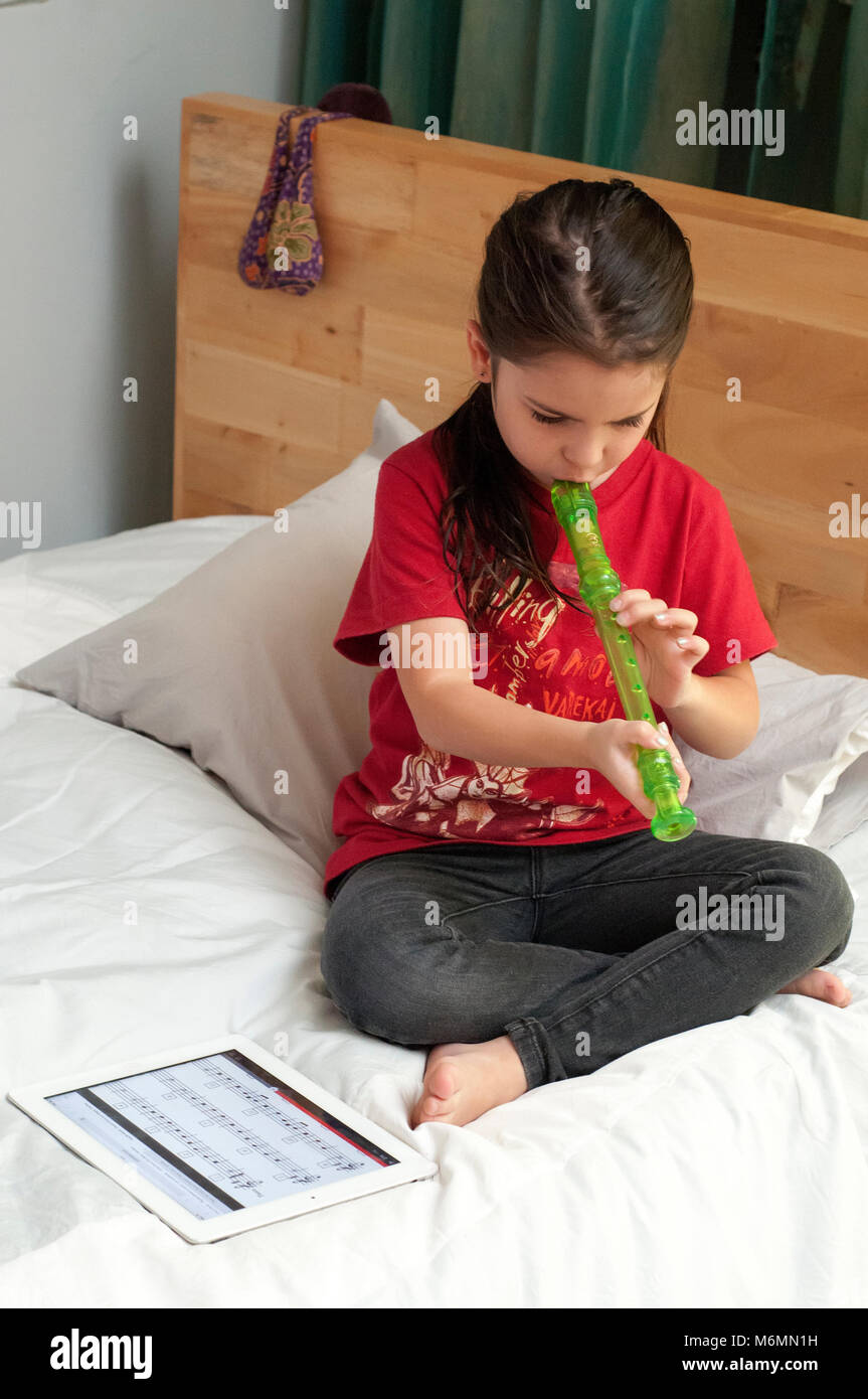 Enfant d'apprendre à jouer la flûte avec l'aide de vidéos en ligne Banque D'Images