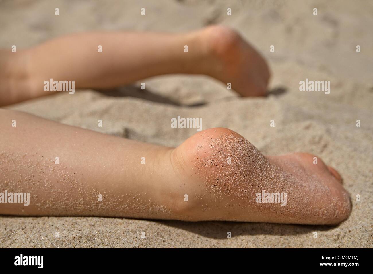 Heureux les pieds nus sur une plage de sable. Pieds couverts de sable. Ensoleillé. Profondeur de champ. Banque D'Images