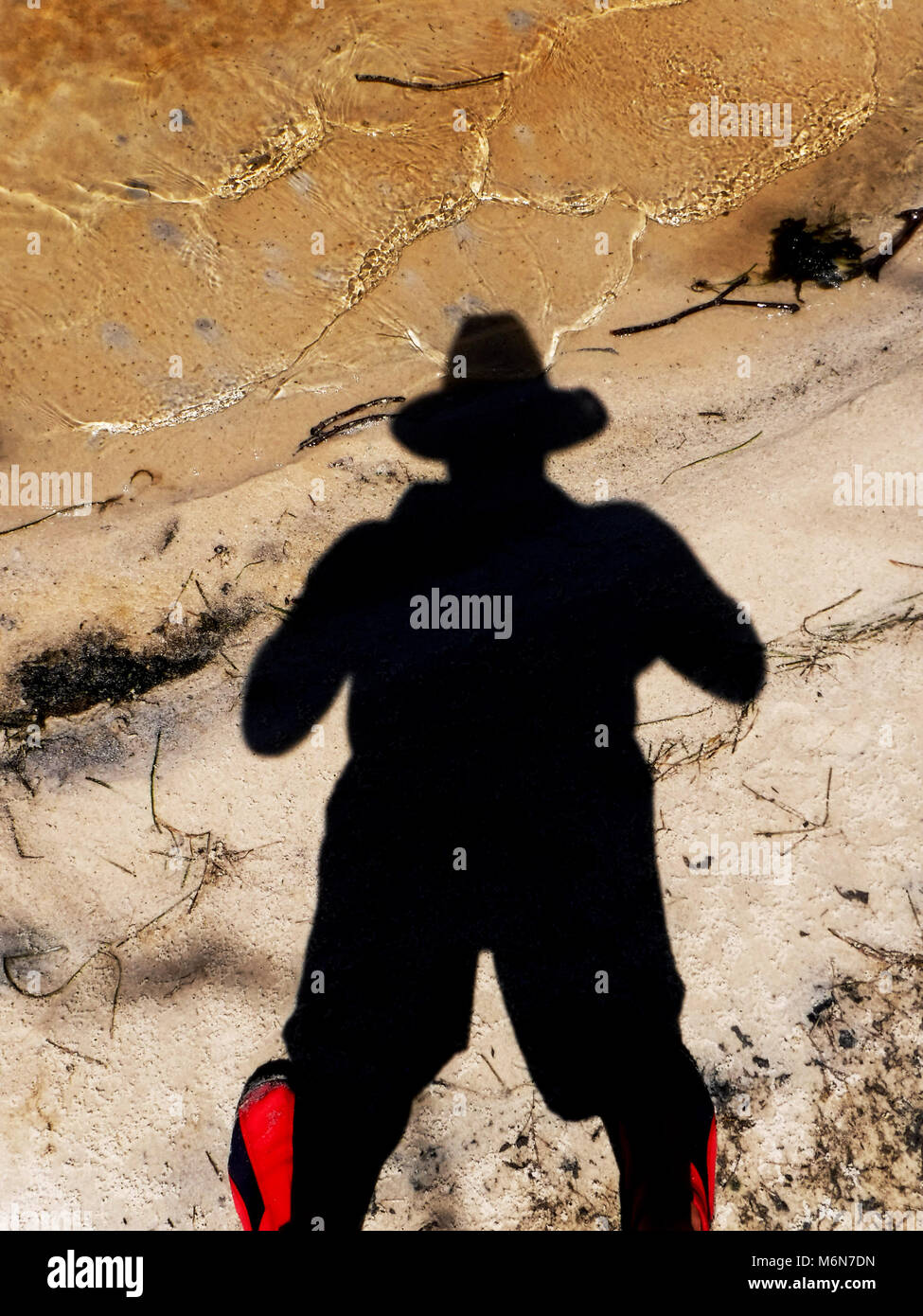 Ombre de l'homme avec chapeau contre le sable et l'eau Banque D'Images