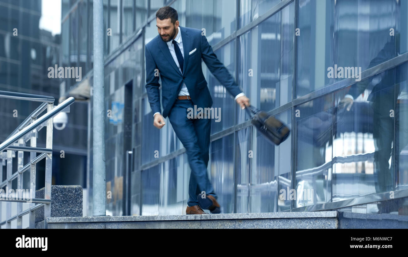 Happy Smiling Business Man avec un sac descend les escaliers, il est dans le quartier des affaires. Il est en hâte. Banque D'Images