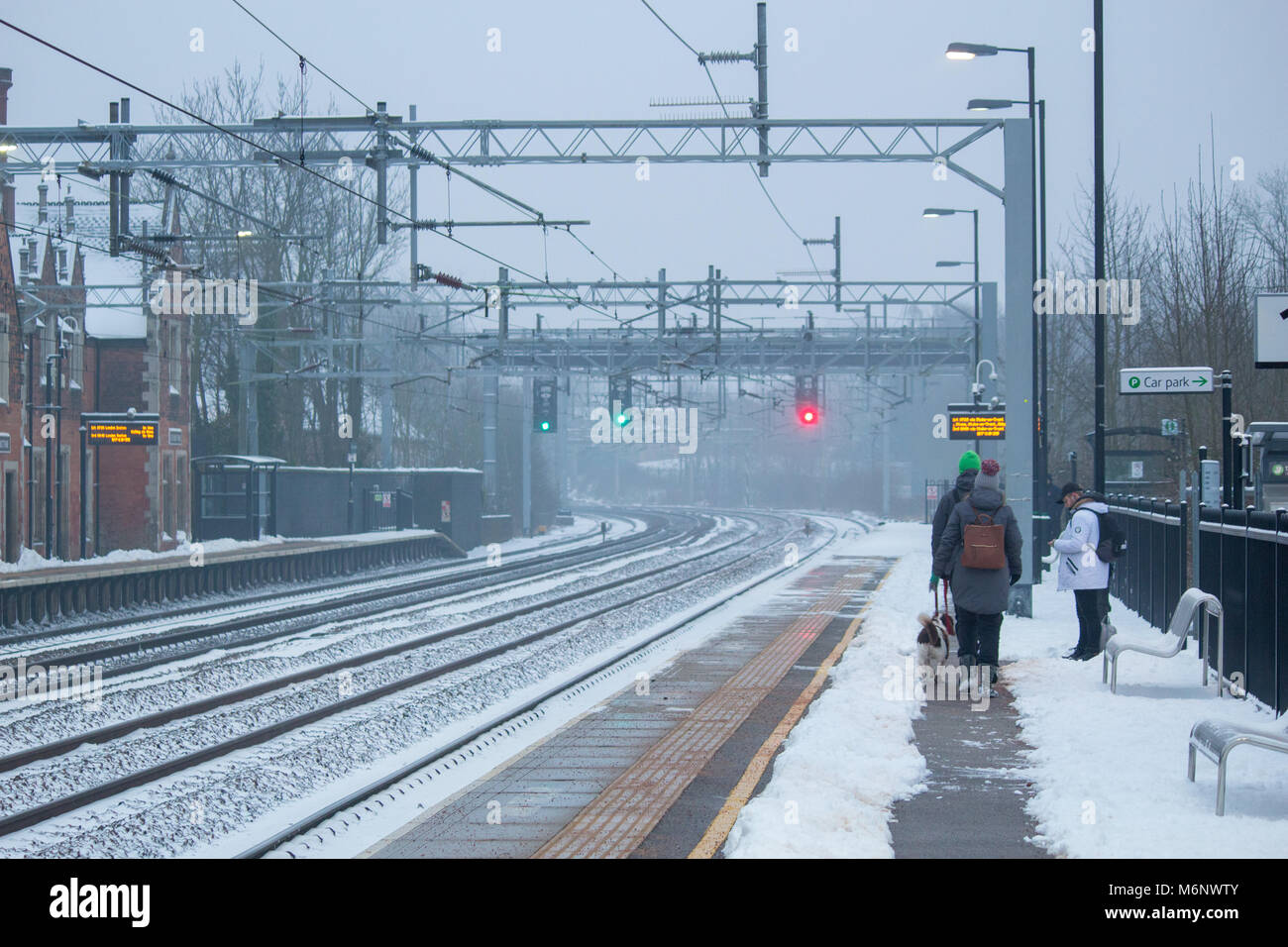 Passagers attendent sur une plate-forme à un Atherstone gare couvert de neige. La neige a été effacé pour faire une voie sur les plates-formes. Banque D'Images