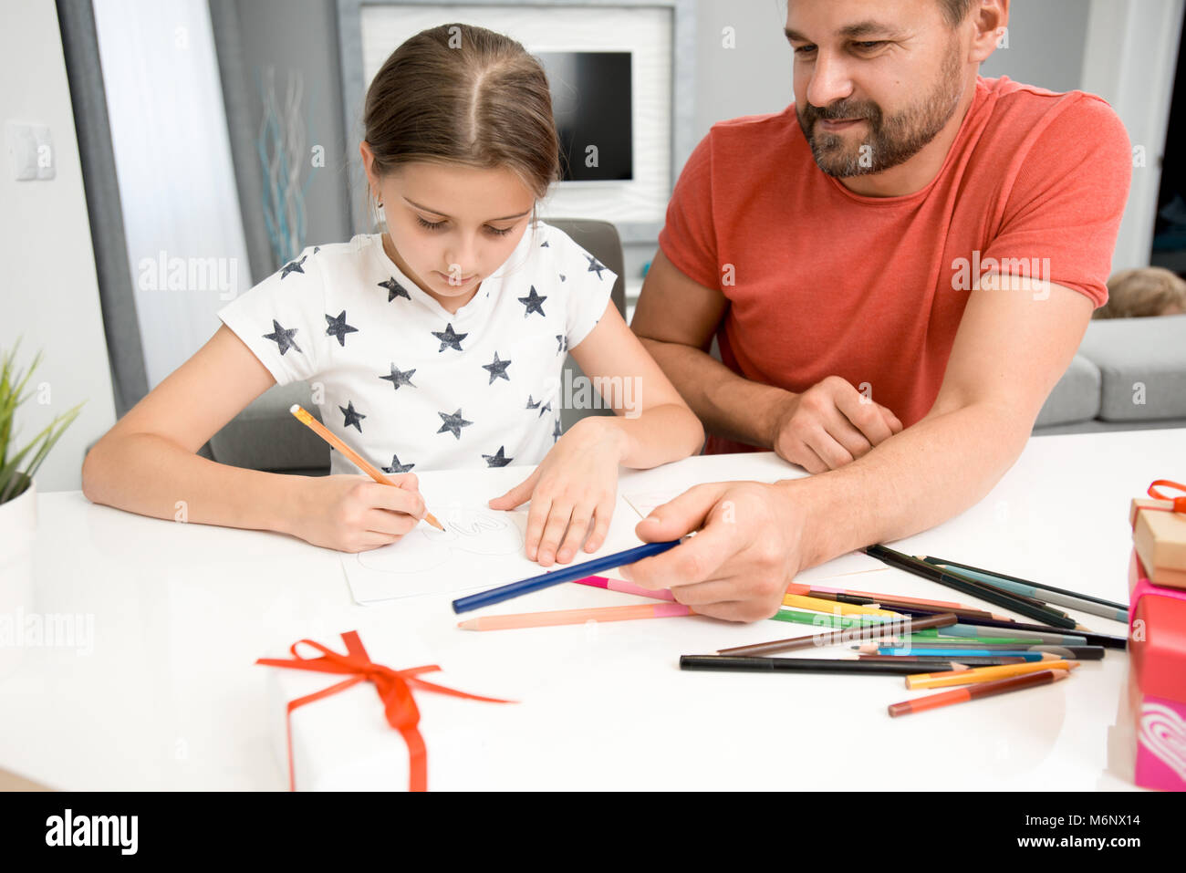 Portrait de père barbu aider petite fille fait main dessin carte pour la fête des mères à la maison in modern living room Banque D'Images