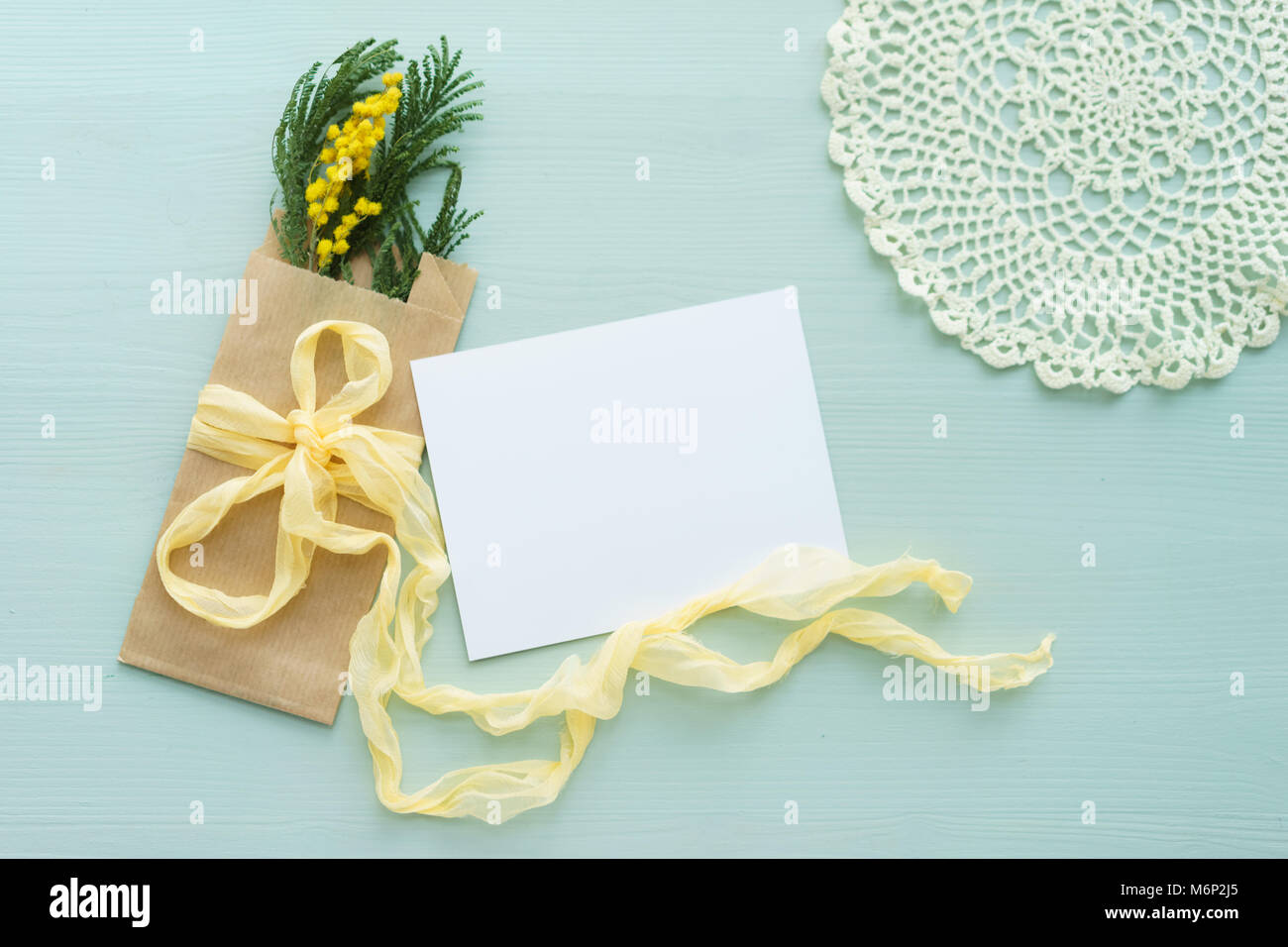 Brunch mimosa dans sac enveloppe kraft sur un fond bleu, l'arc de soie jaune avec du blanc carte vierge pour le texte, napperon au crochet Banque D'Images