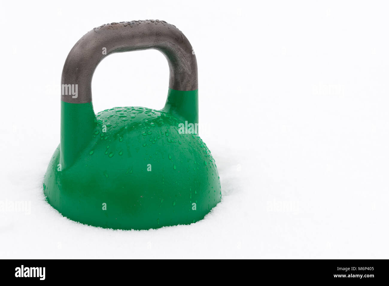 La concurrence verte couverte de kettlebell les gouttelettes d'eau à l'extérieur dans la neige. Copie potentiel espace à droite de kettlebell. Banque D'Images