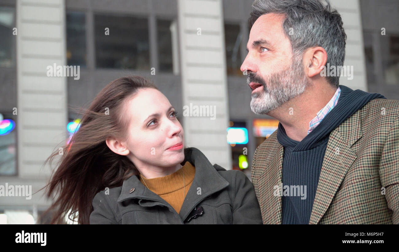 Hipster deux meilleurs amis assis sur le trottoir de la ville de New York en plein air au banc nuit sourire et parler tout en ayant une bonne conversation. C attrayant Banque D'Images