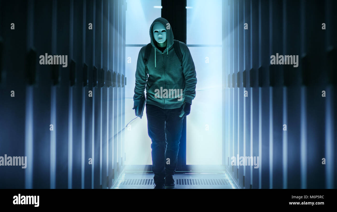 Hacker masqués portant des sweats à capuche promenades dans le cadre du Corridor du centre de données. Banque D'Images