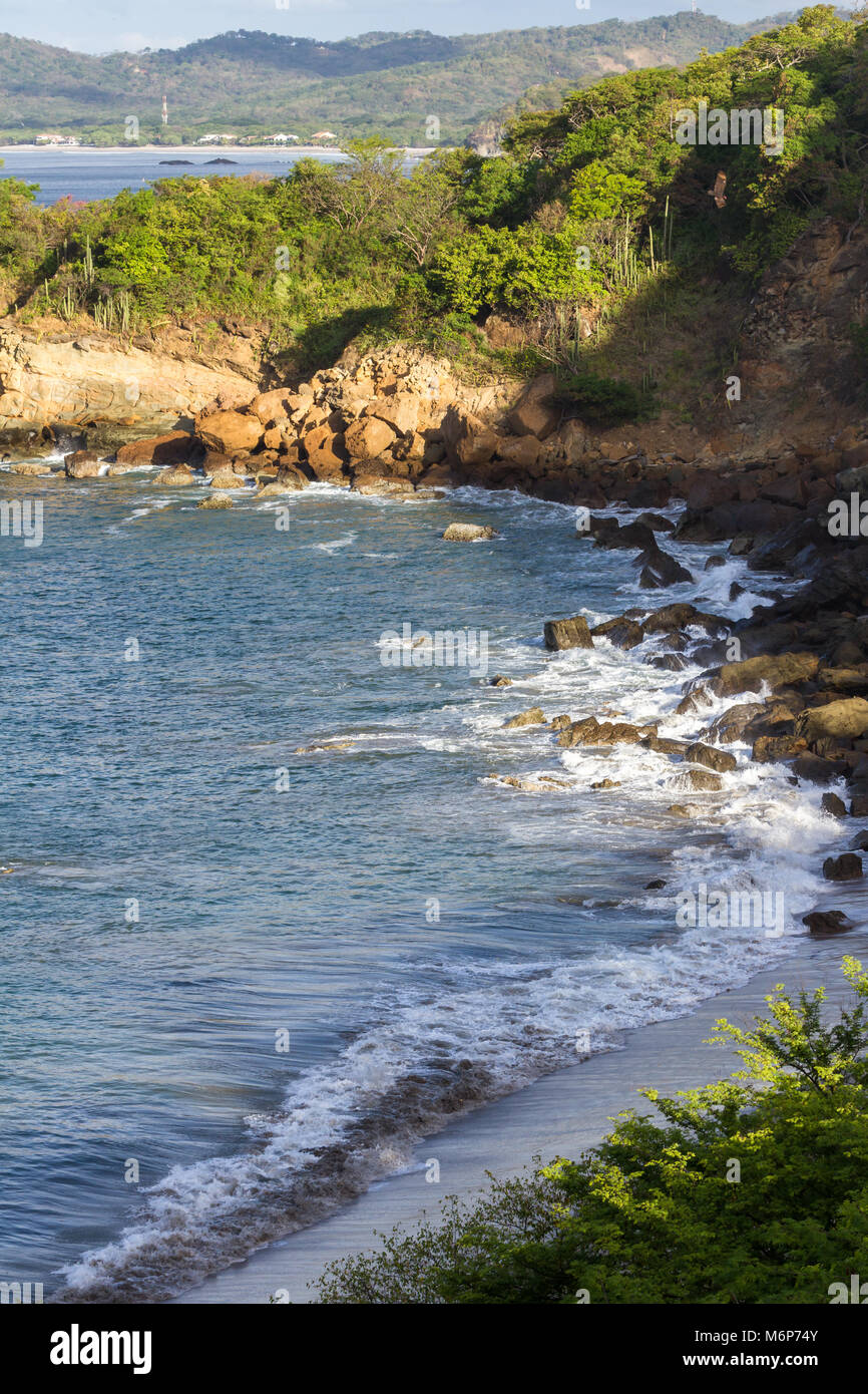 Gros plan d'une section de plage de Playa Redonda, le Nicaragua avec les vagues se briser sur les rochers dans cette baie protégée Banque D'Images