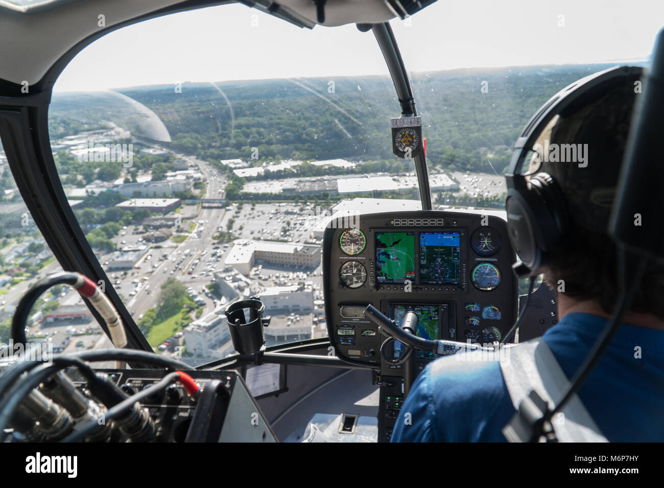 New York City, vers 2017 : vue aérienne à l'intérieur du poste de pilotage d'hélicoptère survolant la zone de banlieue sur la route un jour d'été. Sur l'épaulement de pi Banque D'Images