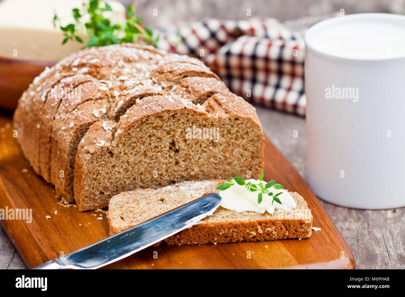 Tranches de pain irlandais stoneground soda avec du beurre et le thym sur la table en bois Banque D'Images