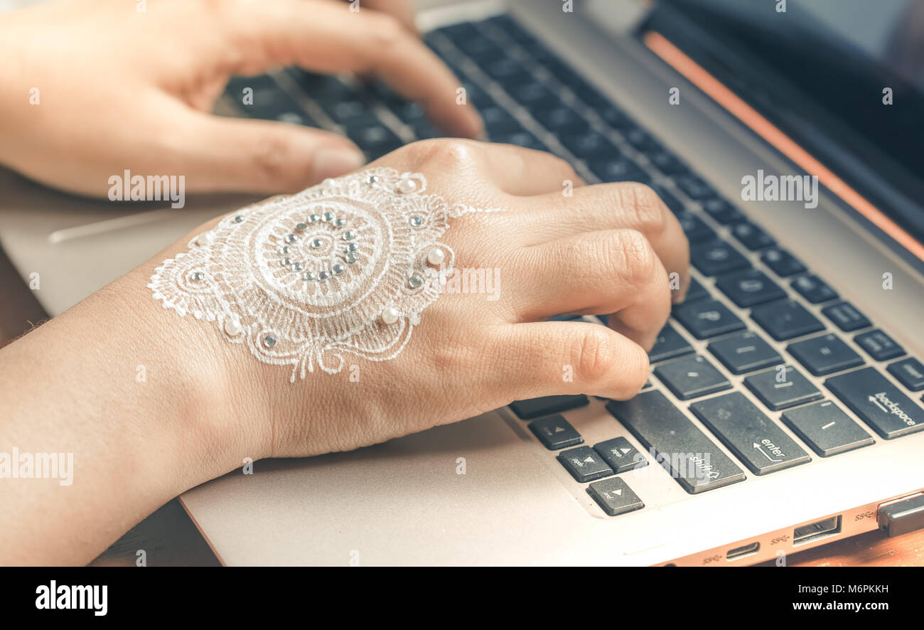 Part de la saisie sur clavier d'ordinateur portable. Femme avec la main de henné design concept art mandala de travailler de la maison. Banque D'Images