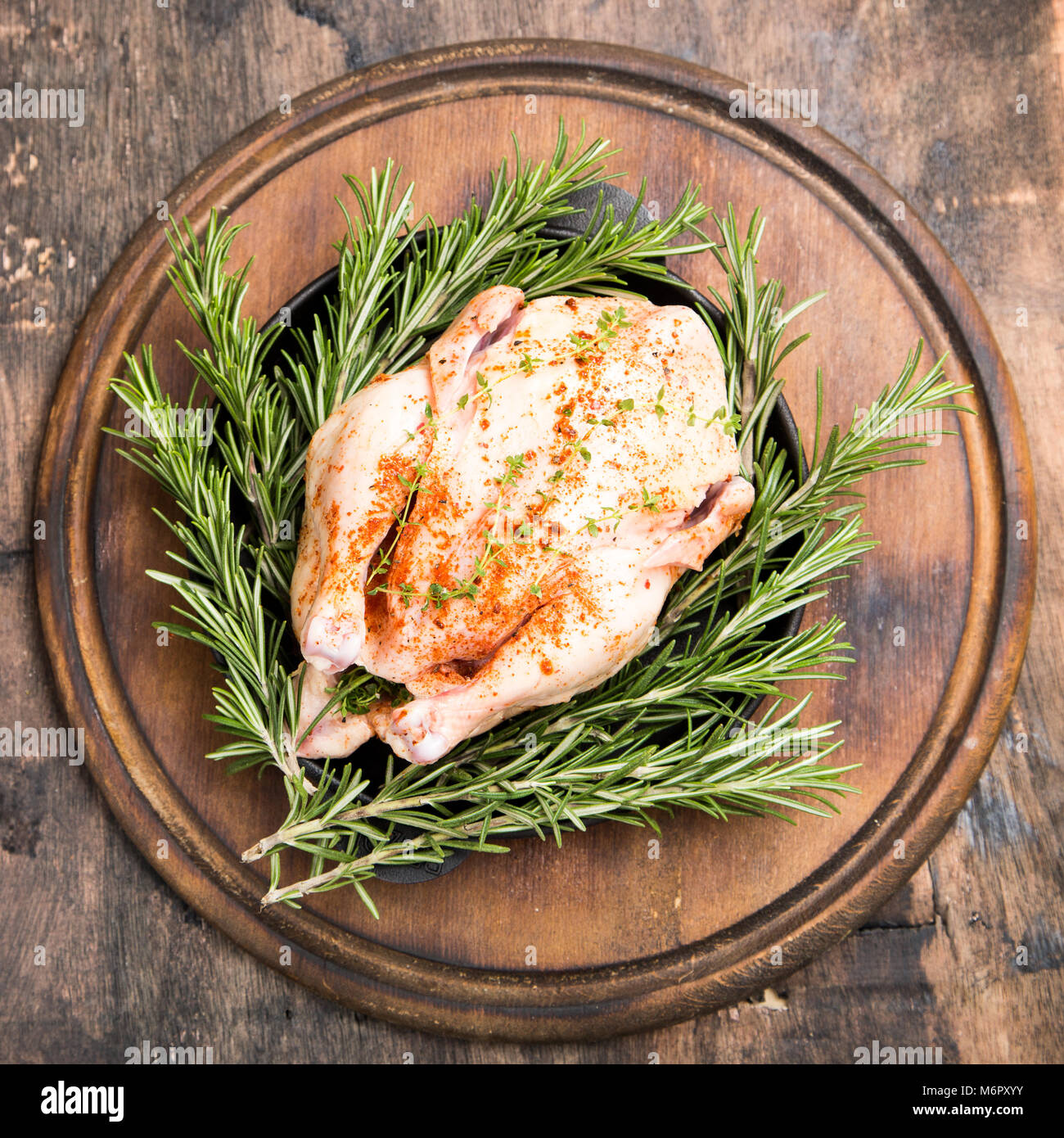 Poulet cru entier sur planche à découper en bois. Les carcasses de poulet aux épices. Banque D'Images