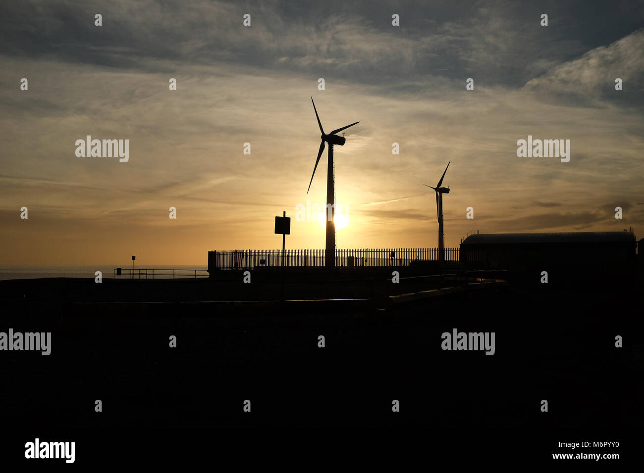 Plage Southwick, Port Shoreham, West Sussex, Angleterre. Voir la silhouette de deux éoliennes. Banque D'Images