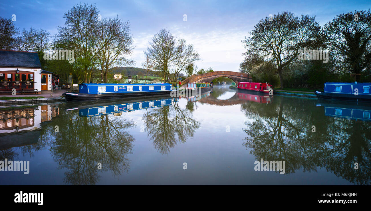 Sur le bassin du Canal Grand Union canal montrant l'un des pubs,plusieurs narrowboats et une bosse soutenu pont. Banque D'Images