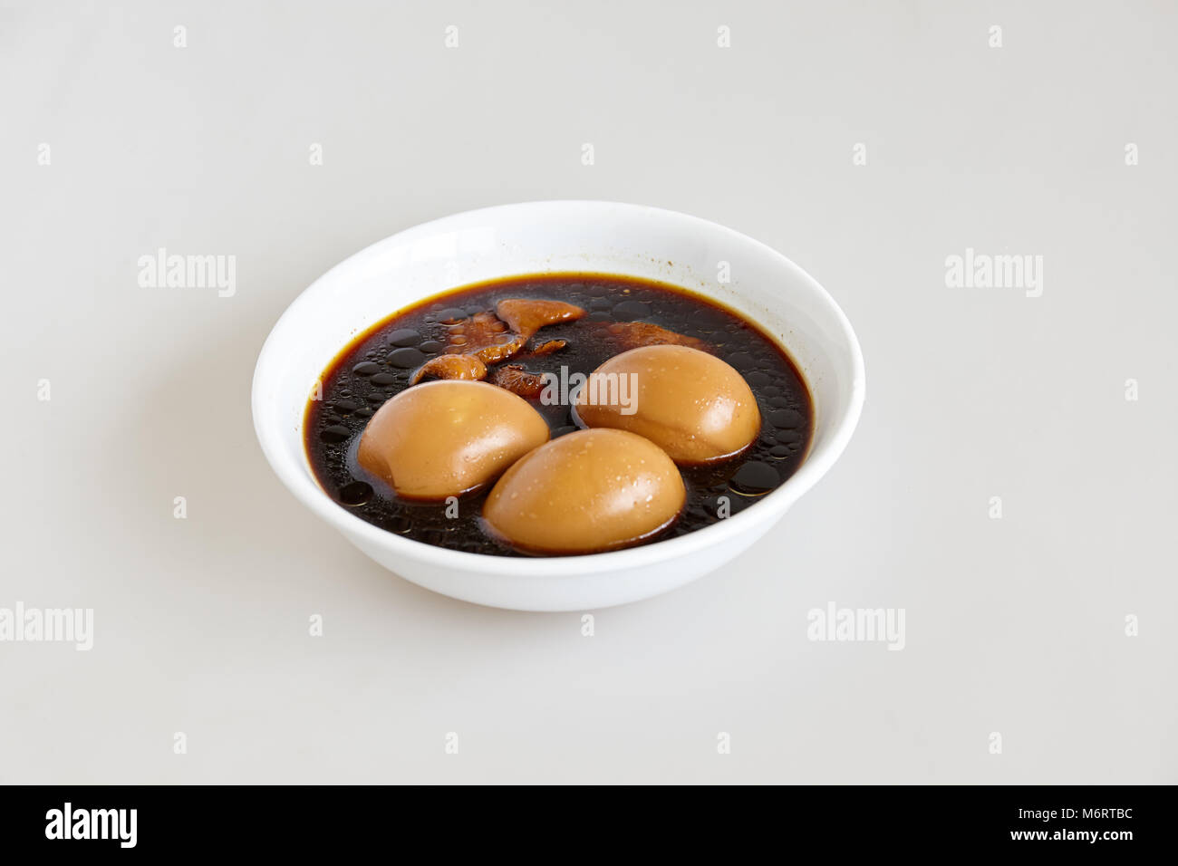Les oeufs durs et le porc et le tofu dans la sauce brune douce sauce sur le fond blanc (Thai's nommé Kai-Pa-Lo)- Vue de dessus Banque D'Images