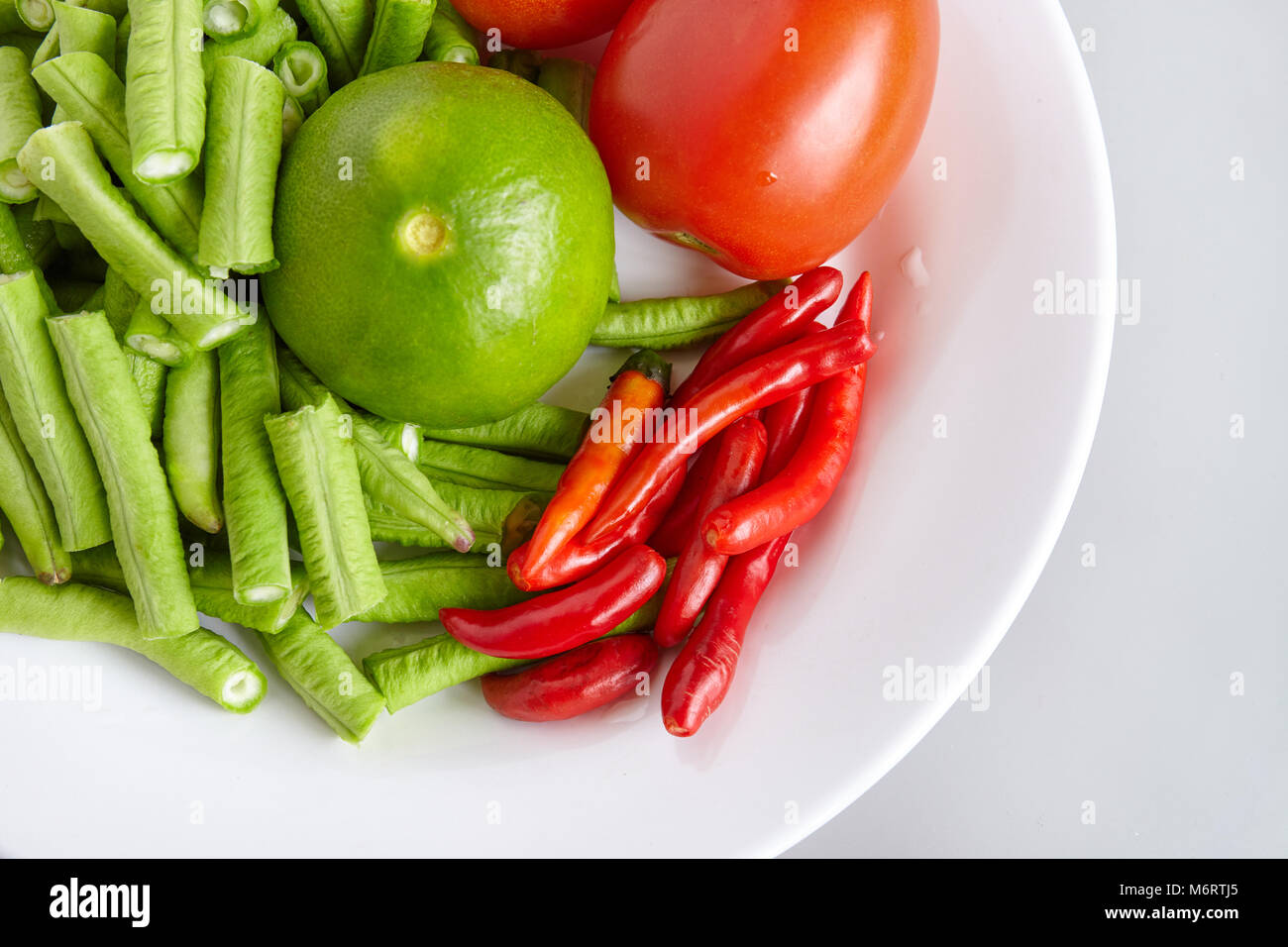 Les matières d'ingrédients frais pour la nourriture thaïe pour faire de longs haricots verts salade, tomate, citron vert - Vue de dessus, fermé Banque D'Images