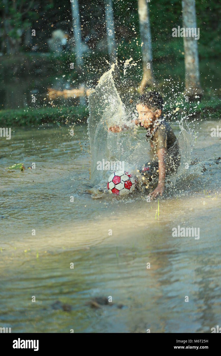 Enfance heureuse, de boue, jouer, Football, avoir du plaisir avec la nature, profiter de leur enfance, les enfants football,souvenirs, s'amusant, pour les enfants, cycle arbre avec boy, game Banque D'Images