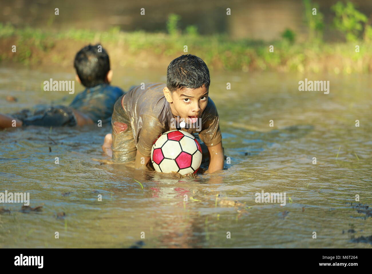 Enfance heureuse, de boue, jouer, Football, avoir du plaisir avec la nature, profiter de leur enfance, les enfants football,souvenirs, s'amusant, pour les enfants, cycle arbre avec boy, game Banque D'Images