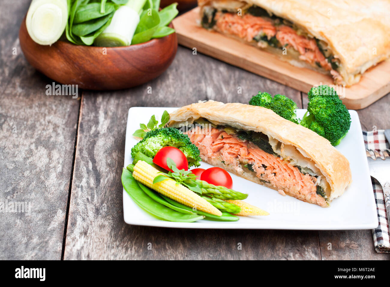 Filet de saumon sur les poireaux et spinachbaked en feuilleté aux légumes Banque D'Images