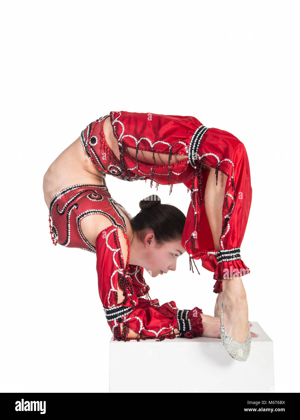 Exercices de gymnastique Acrobat n , l'image isolé sur un fond blanc. Jeune femme athlétique dans un justaucorps rouge, la pratique de l'acrobatie. Banque D'Images