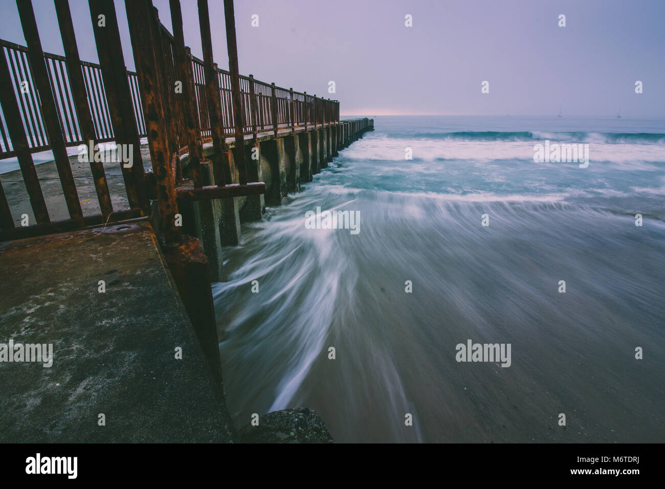 L'exposition longue photo de vagues se brisant sur la plage de McGurk jetée sur un jour brumeux au crépuscule, les orteils Beach, Playa Del Rey, en Californie Banque D'Images
