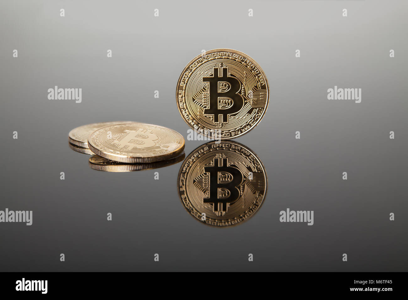 Devise Crypto. Les bitcoins or sur verre gris avec reflet Banque D'Images