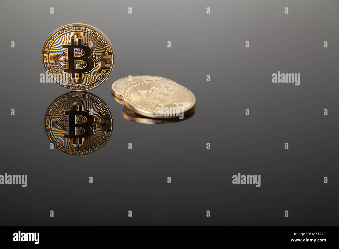 Devise Crypto. Les bitcoins or sur verre gris avec reflet Banque D'Images