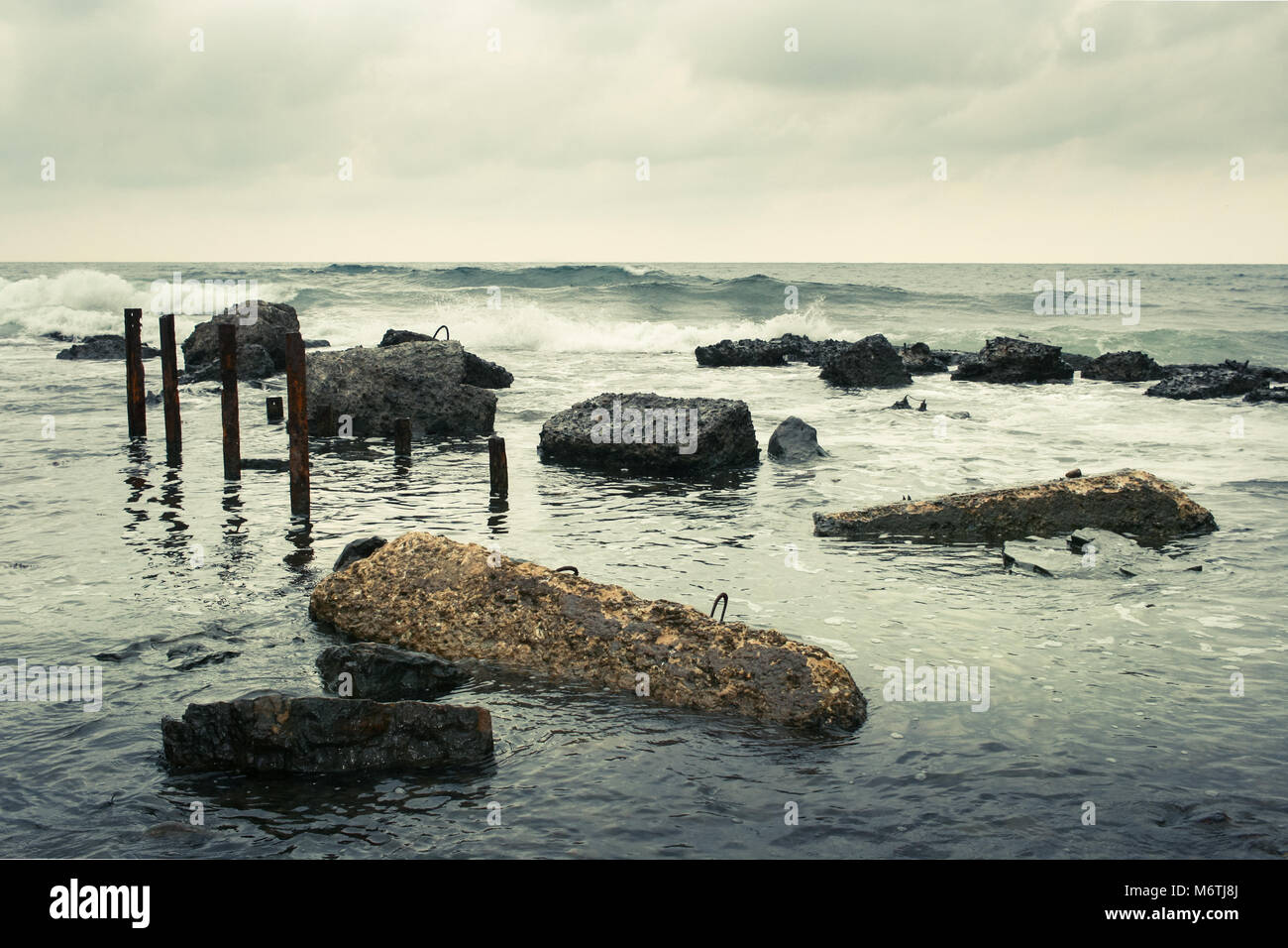 Tuyaux rouillés et le béton couché dans la mer. Banque D'Images