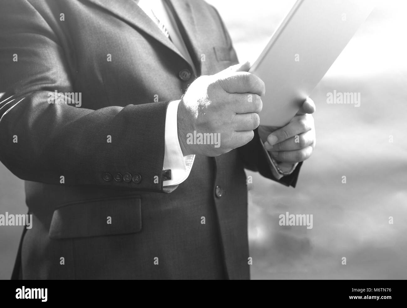 Close - up d'un adulte businessman standing in suit et à l'aide d'un comprimé, tourné en noir et blanc Banque D'Images