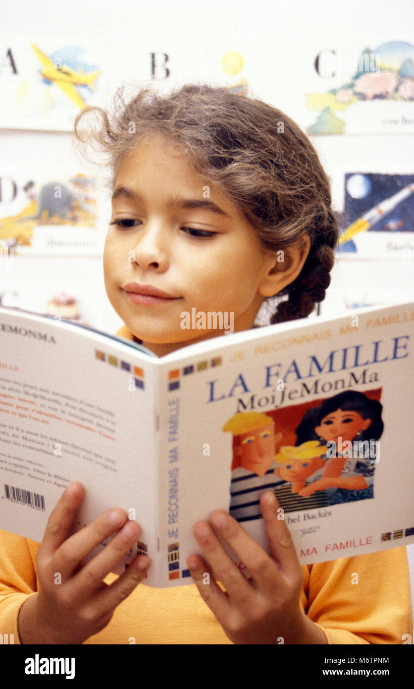 Petite fille lisant le livre français la famille Banque D'Images