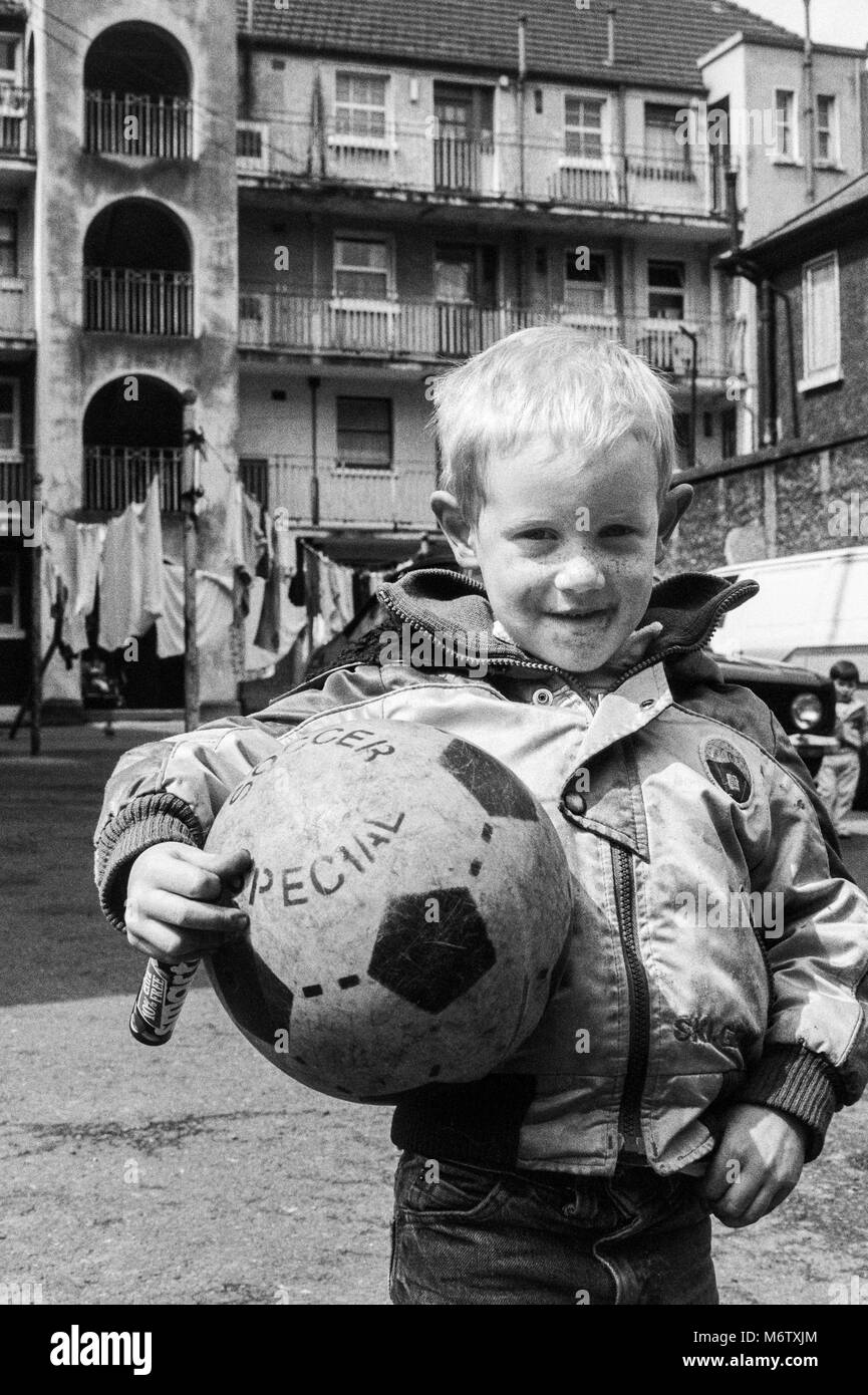 Jeune garçon avec le football dans la cour d'un immeuble bloc dans le centre-ville de Dublin, Irlande, photographie d'archives de Avril 1988 Banque D'Images