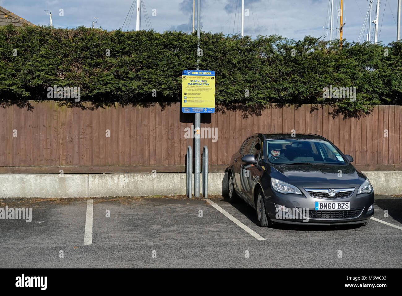 L'homme en attente dans sa voiture dans un parking de supermarché Banque D'Images