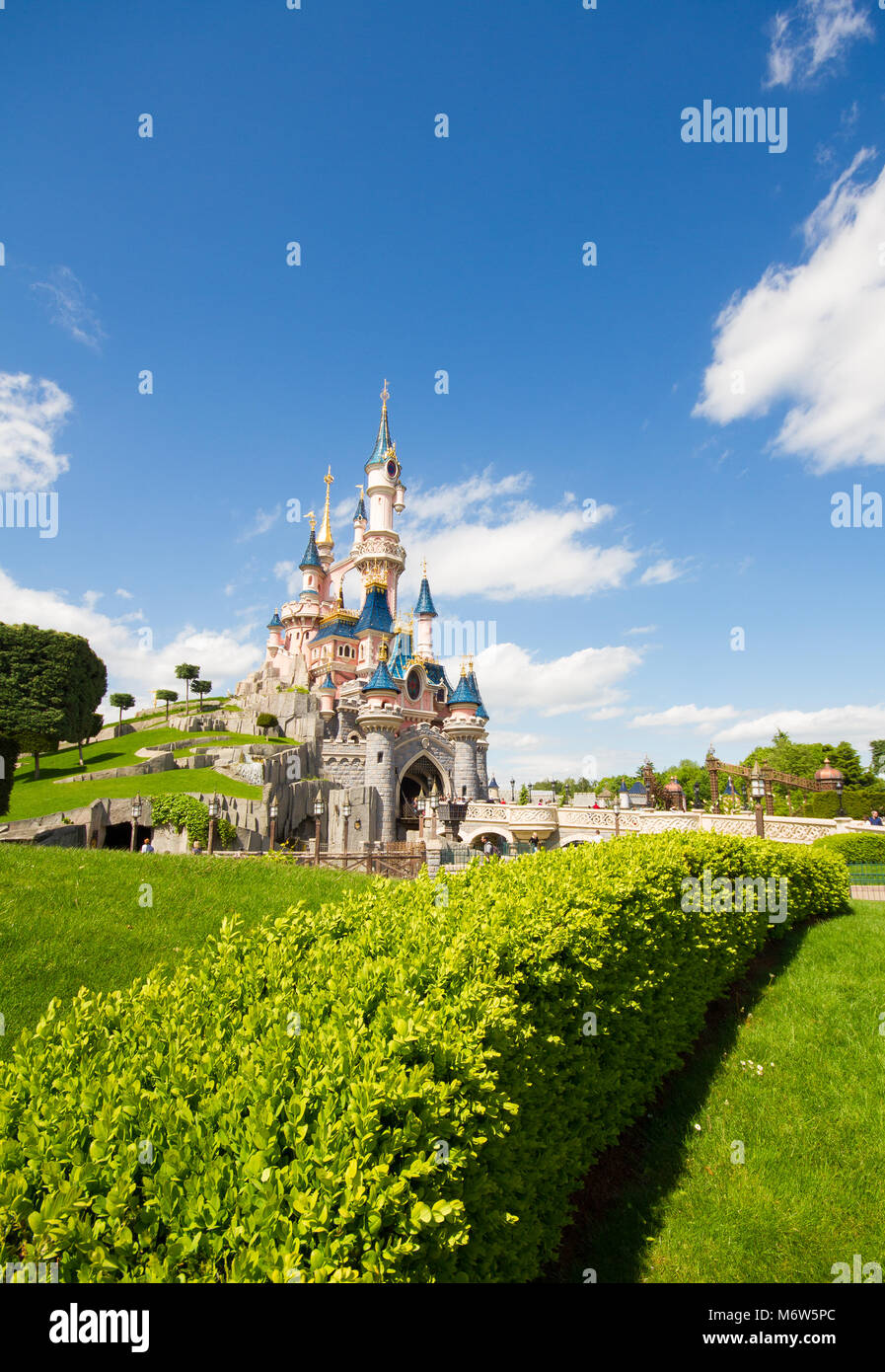 Une image colorée en orientation portrait de du Château de La Belle au bois dormant à Disneyland Paris, montrant de magnifiques jardins et de ciel bleu. Banque D'Images