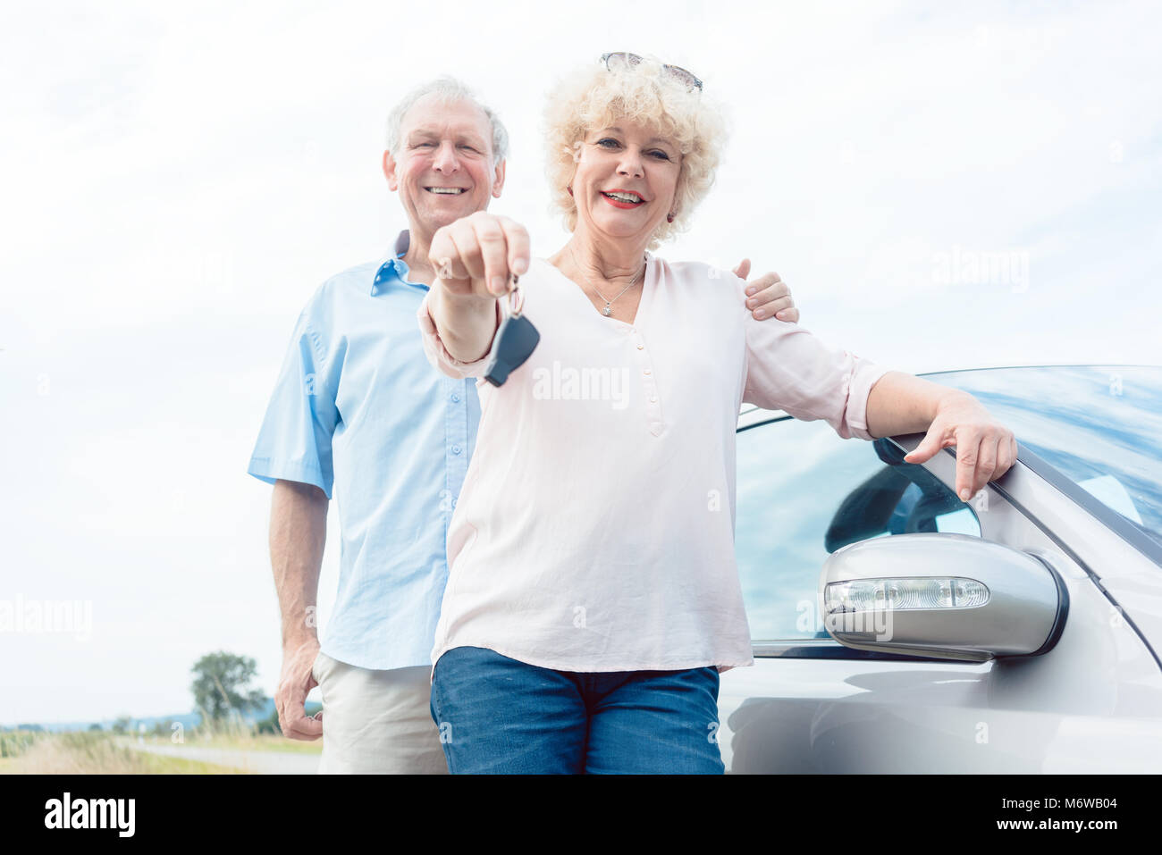 Close-up de la main d'un senior woman montrant les clés de sa voiture tout en se posant à côté de sa partenaire comme confiant les conducteurs âgés Banque D'Images