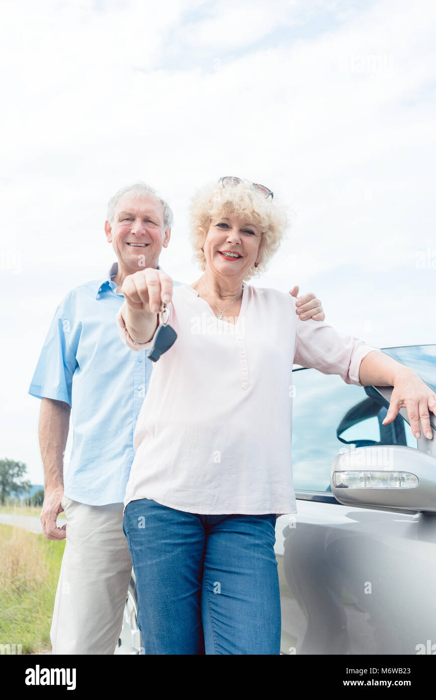 Close-up de la main d'un senior woman montrant les clés de sa voiture tout en se posant à côté de sa partenaire comme confiant les conducteurs âgés Banque D'Images