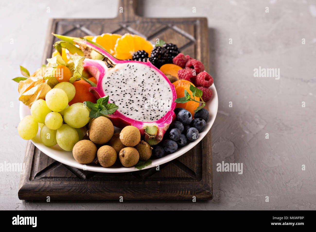 Assiette de fruits exotiques avec du raisin, fruit du dragon, longane et  fruit de la passion Photo Stock - Alamy