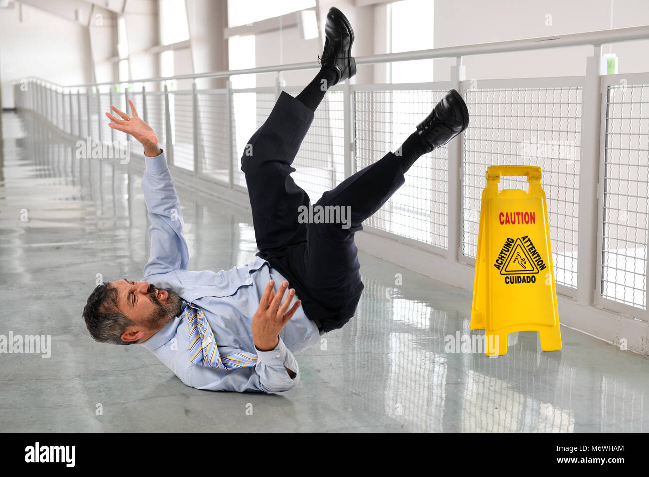 Hispanic businessman tombant sur sol humide à l'intérieur office building Banque D'Images