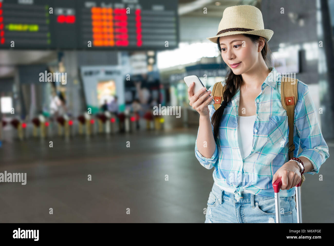 Billet d'Asian woman holding mobile phone reading text message dans la Taiwan high speed rail station hall en attendant le train qui arrivait. Banque D'Images