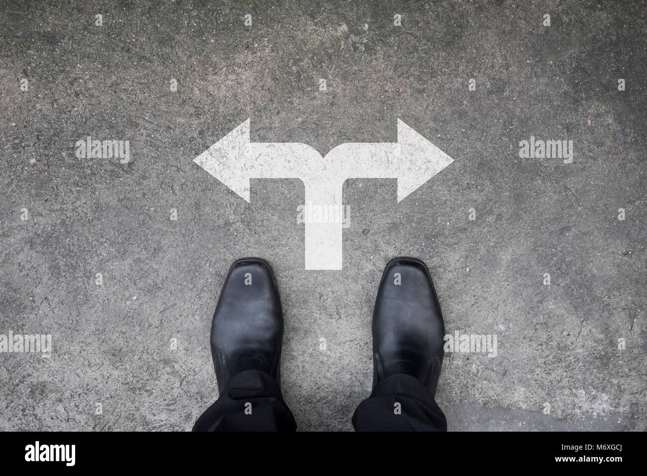 Chaussures noires debout à la croisée des chemins sur un sol en béton Banque D'Images