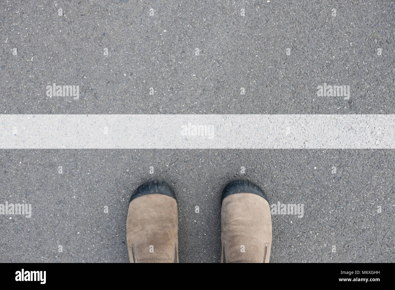 Chaussures en daim marron debout sur le plancher de béton d'asphalte en face de ligne blanche Banque D'Images