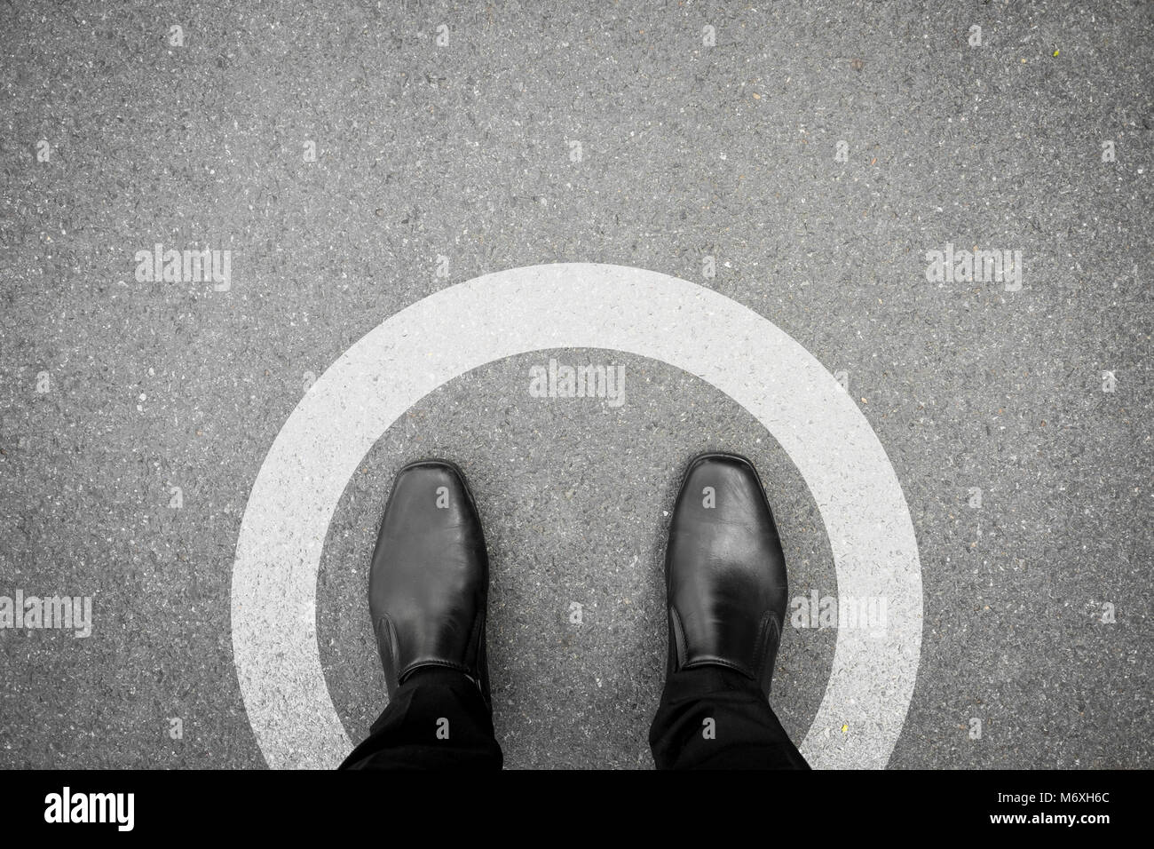 Chaussures noires debout en cercle blanc sur le plancher de béton d'asphalte Banque D'Images