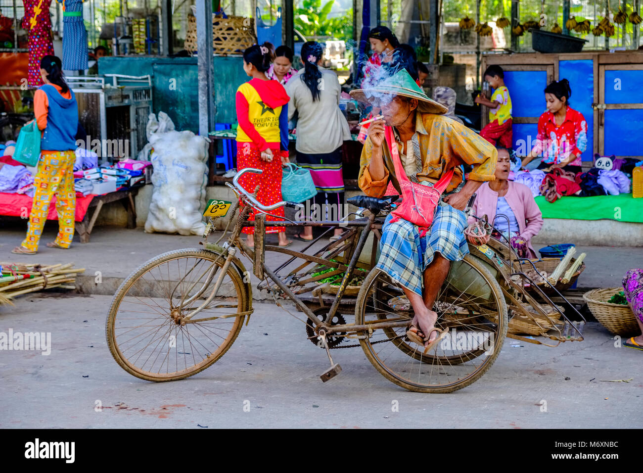 Un vélo rikscha pilote est assis sur son rikshaw, d'attente pour les clients et fumer un cigare, un Cheerot Banque D'Images