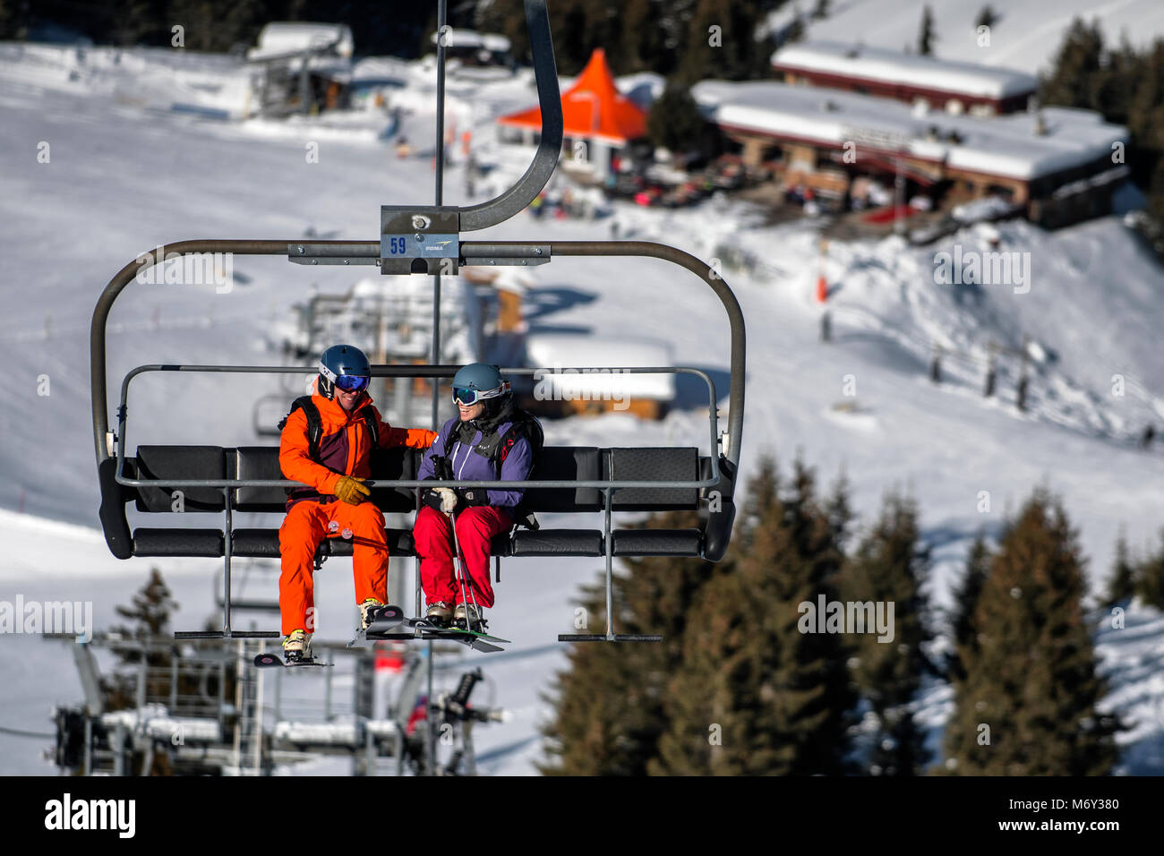 Un moniteur de ski homme parle à une femme sur un télésiège dans la station alpine de Courchevel. Banque D'Images