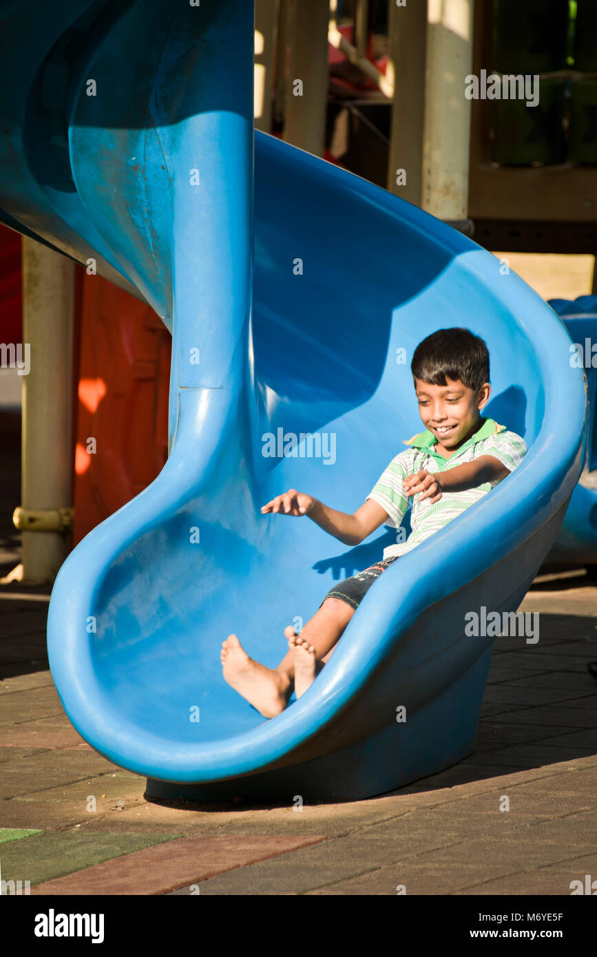 Portrait vertical d'un garçon sur la diapositive dans Viharamahadevi Park, anciennement connu sous le nom de Victoria Park à Colombo, Sri Lanka. Banque D'Images