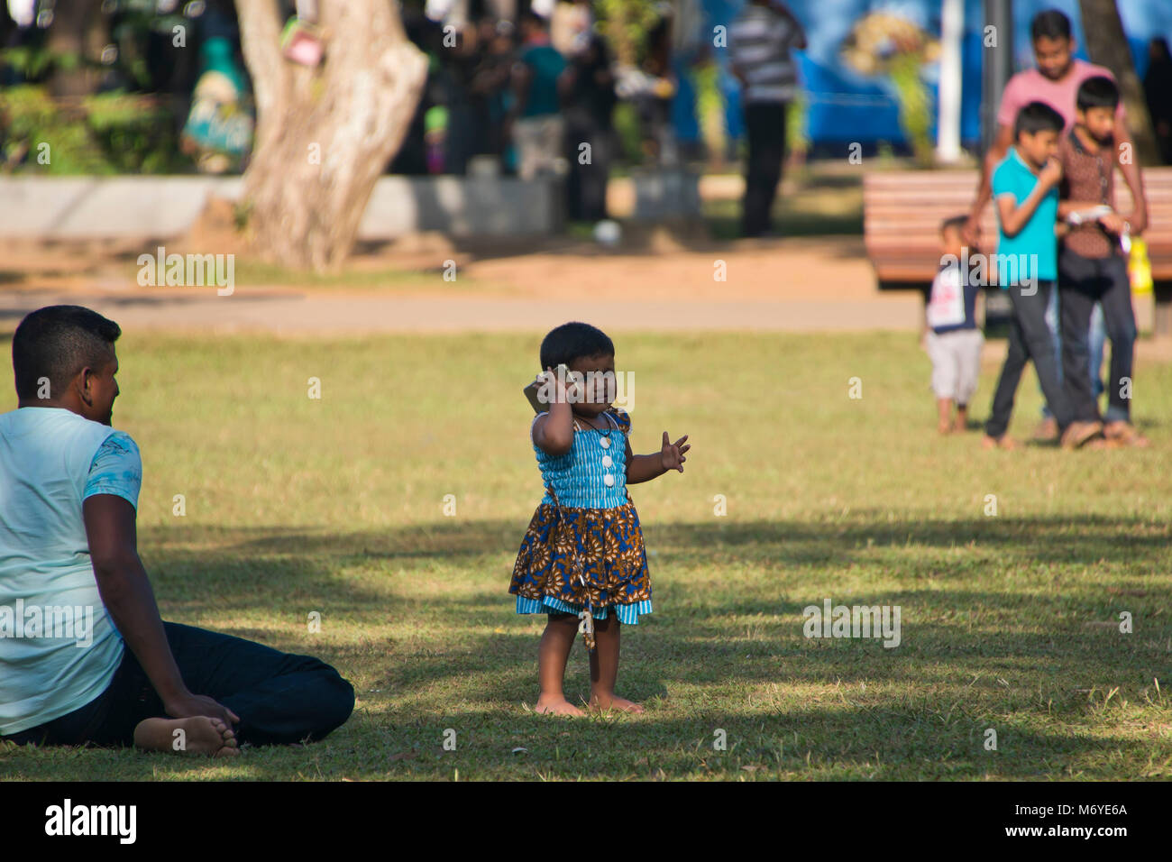 Vue horizontale d'une petite fille jouant avec un téléphone mobile en Viharamahadevi Park, anciennement connu sous le nom de Victoria Park à Colombo, Sri Lanka. Banque D'Images