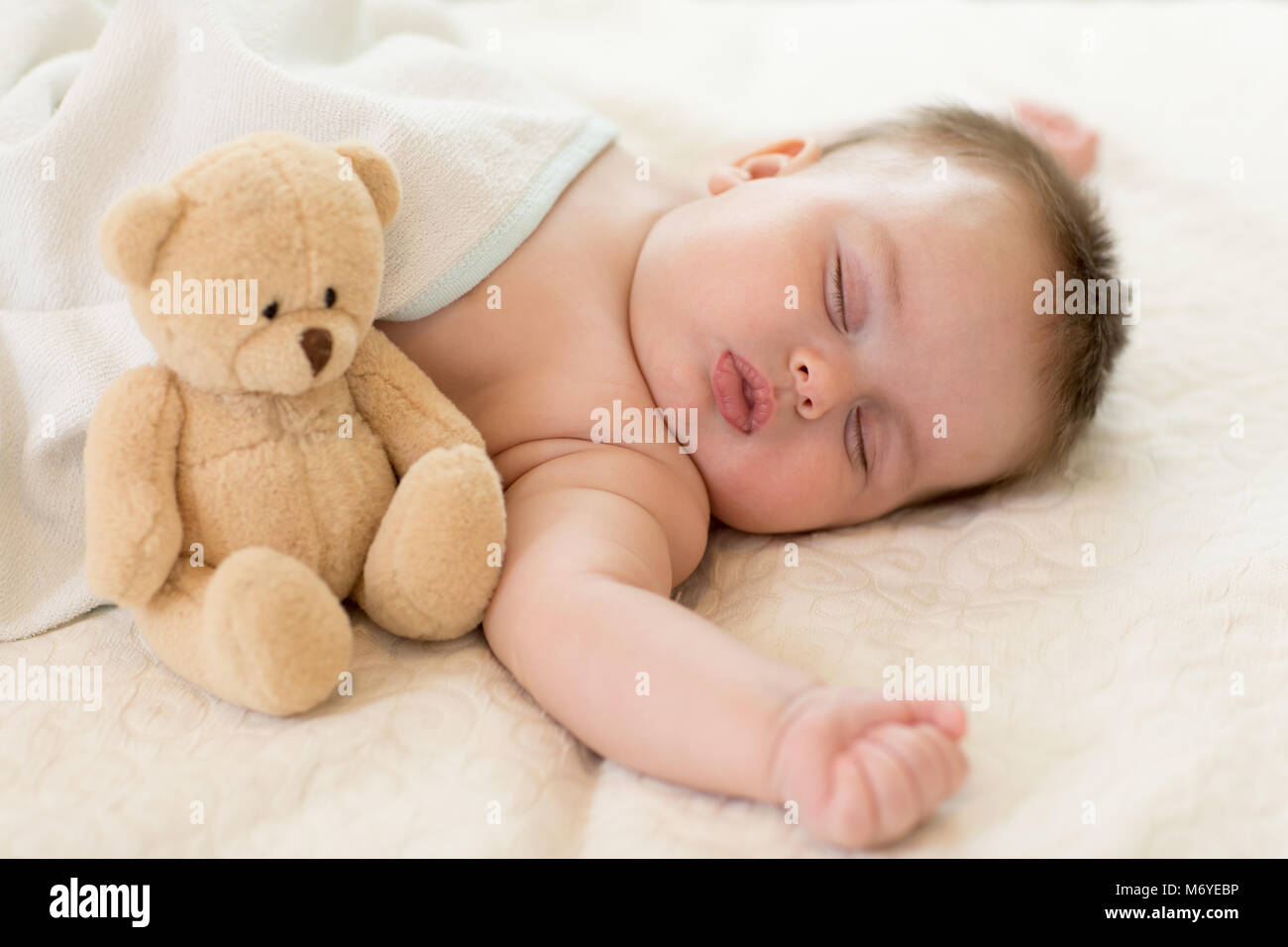 Nouveau-né bébé à dormir dans le lit avec nounours. Banque D'Images