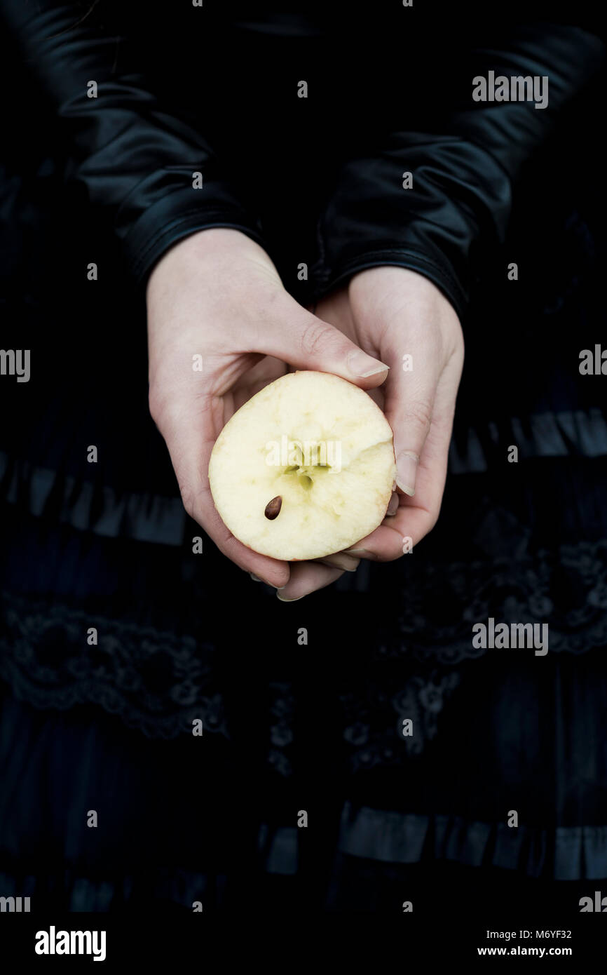 Woman's hands holding une tranche de pomme montrant l'étoile de cinq et une graine de forme Banque D'Images