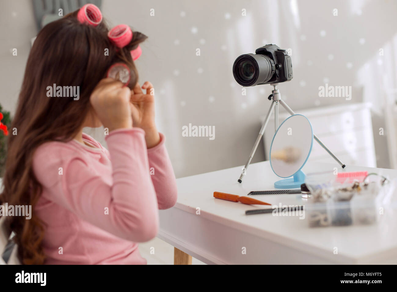 Belle fille à l'aide de rouleaux de cheveux et l'enregistrement vidéo tutoriel Banque D'Images