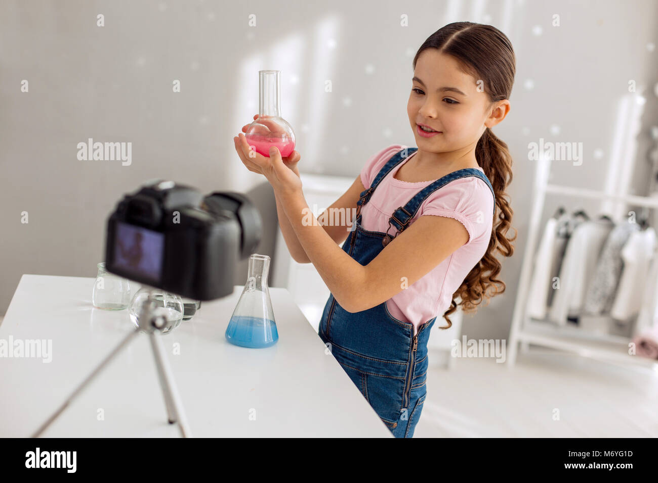 Fille agréable montrant la fiole avec de l'appareil à des produits chimiques Banque D'Images