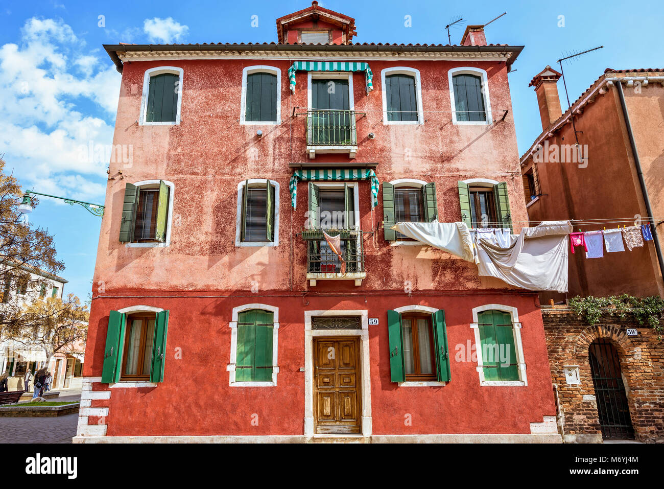 Vue l'heure avancée de bâtiment rouge avec de la peinture et de blanchisserie en plein air de séchage. Architecture historique bâtiments et ciel bleu avec des nuages. Murano Banque D'Images