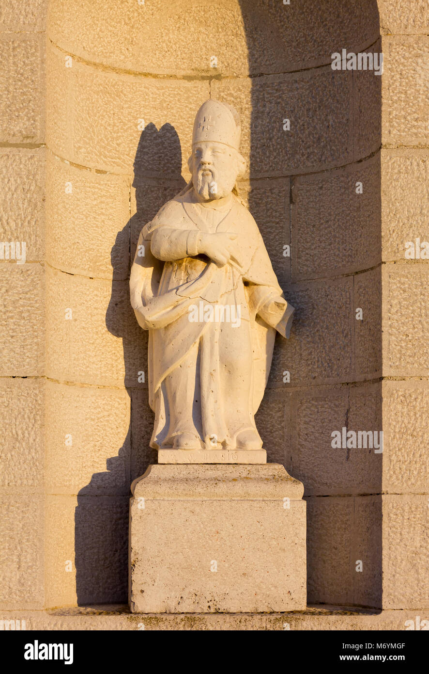 Statue de Saint Blaise sur la façade d'une église de campagne au coucher du soleil Banque D'Images